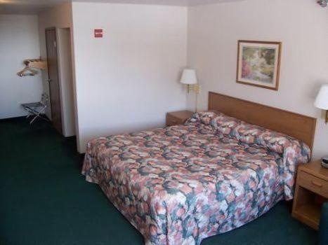a hotel room with a bed and a dresser at Budget Host Inn & Suites North Branch in North Branch