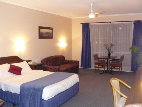a hotel room with a bed and a chair and a table at Australia Park Motel in Albury
