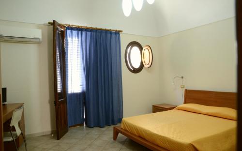 サン・ヴィート・ロ・カーポにあるAcqua di Mare B&Bのベッドルーム1室(ベッド1台、青いカーテン付きの窓付)