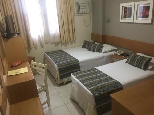a hotel room with two beds and a desk at San Michel Palace Hotel in Taubaté
