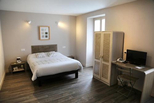 Schlafzimmer mit einem Bett und einem Schreibtisch mit einem TV in der Unterkunft Logis La Garissade in Labastide-Murat