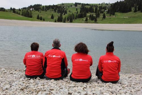 a group of people sitting on the shore of a lake at Chalet Laila in Folgaria