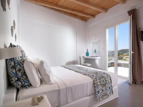 biała sypialnia z łóżkiem i oknem w obiekcie Lithos Luxury Rooms (Adults Only) w mieście Adamas