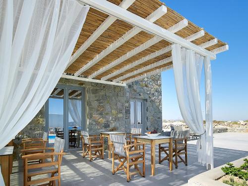 a patio with a table and chairs and a stone wall at Lithos Luxury Rooms (Adults Only) in Adamantas