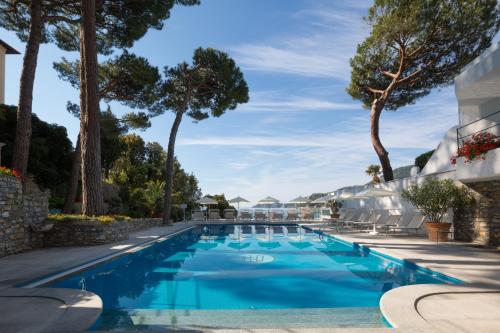 een zwembad met blauw water en bomen bij Imperiale Palace Hotel in Santa Margherita Ligure