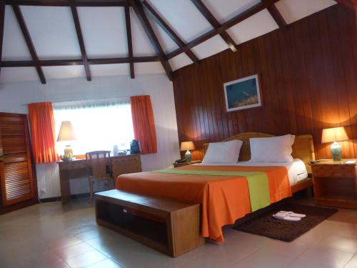 ein Schlafzimmer mit einem großen Bett mit einer orangefarbenen Decke in der Unterkunft Club Santana Beach & Resort in SantʼAna