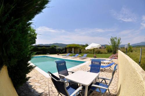 a swimming pool with chairs and a table and an umbrella at Corfu Villa Ermioli with Pool in Giannádes