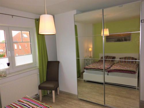 um quarto com uma cama, uma cadeira e um espelho em Ferienwohnung Krabbentaucher 2 em Neßmersiel