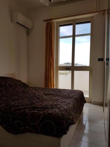 une chambre avec un lit et une grande fenêtre dans l'établissement Apartment Colaianni, à Torre San Giovanni