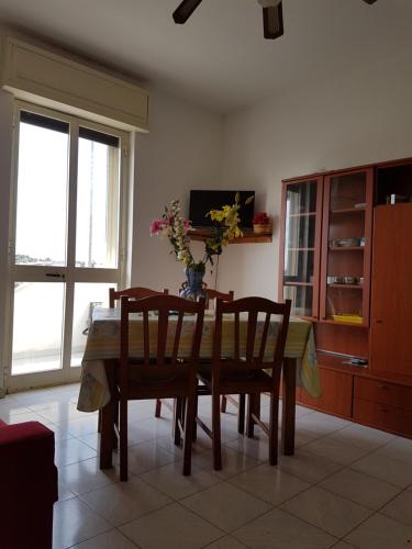 une table à manger avec des chaises et un vase de fleurs dans l'établissement Apartment Colaianni, à Torre San Giovanni