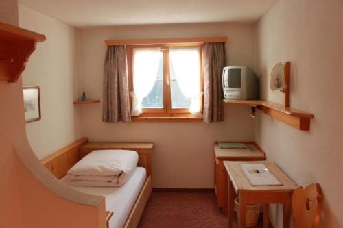 mały pokój z łóżkiem i oknem w obiekcie Hotel Soliva w mieście Sedrun
