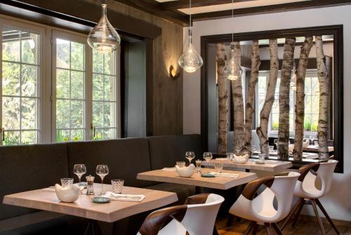 a restaurant with two tables and chairs and windows at LA CHENEAUDIÈRE - Hôtel Spa - Relais & Châteaux - Restaurant étoilé in Colroy-la-Roche