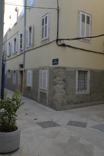 a building with white windows and a street at Apartments and Rooms Oliva in Cres