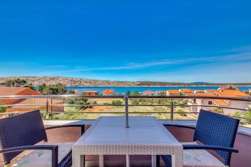 a table and chairs on a balcony with a view of the water at Apartments Host in Rab