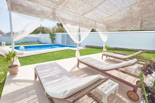 a patio with two lounge chairs and an umbrella at Labreña Hotel in Los Caños de Meca