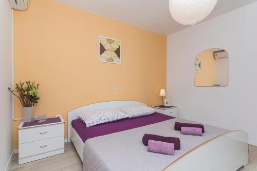 a bedroom with a large bed with purple pillows at Apartments Garmaz in Podgora