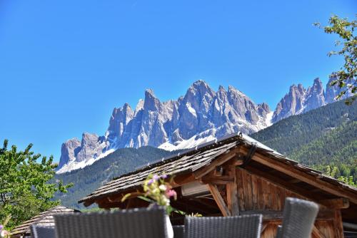a log cabin with mountains in the background at Hotel Gsoihof in Villnoss