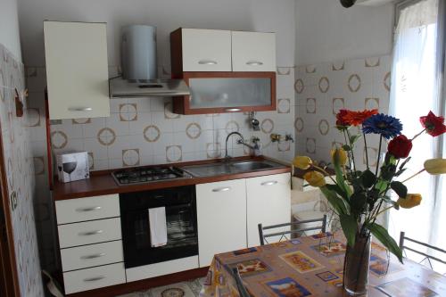 a kitchen with white cabinets and a table with a vase of flowers at B e B CASA DA PINA in Ragusa