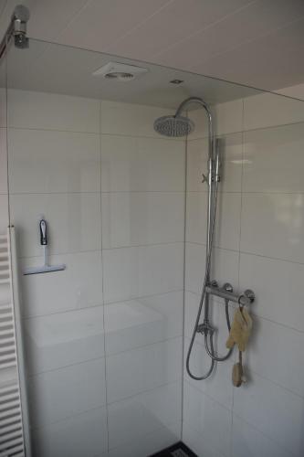 een douche met een douchekop in de badkamer bij Strandleven in Groote Keeten
