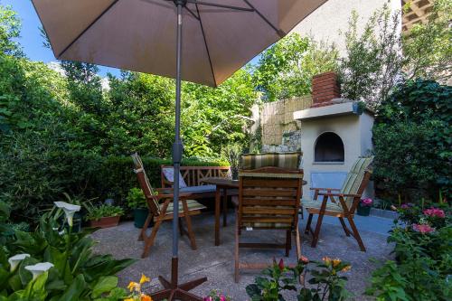 a patio with an umbrella and a table and chairs at Apartments Garmaz in Podgora