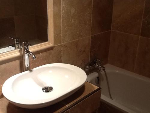 La salle de bains est pourvue d'un lavabo blanc et d'une baignoire. dans l'établissement Hôtel Les Deux Lions, à Riez