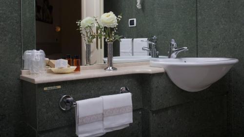 y baño con lavabo, espejo y toallas. en Hotel Feluca, en Bonassola
