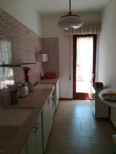 a kitchen with white cabinets and a window and a counter at Palms Villa in Scopello