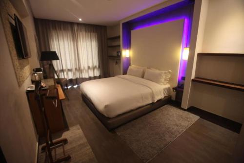 1 dormitorio con cama blanca y luz morada en The Seven Hotel, en Casablanca