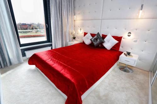 a bedroom with a red bed with a large window at Drim Apartaments in Gdańsk