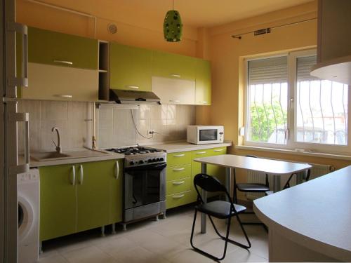 ママイア・ノルドにあるApartament Marea Neagraのキッチン(緑のキャビネット、テーブル、椅子付)