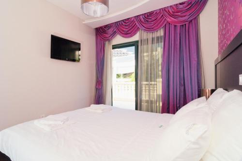 a bedroom with a white bed with purple curtains and a window at Apartments Grifone Lux in Herceg-Novi