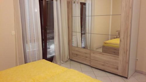 a bedroom with a mirror and a yellow bed at Apartment Smajlovic in Kukci