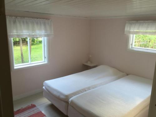 2 Betten in einem Schlafzimmer mit 2 Fenstern in der Unterkunft Ringbomsvägen Holiday Home in Ljugarn
