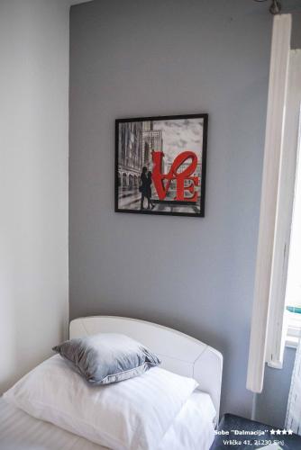 a bedroom with a white bed and a picture on the wall at Apartment/Room ''Dalmacija'' SINJ in Sinj