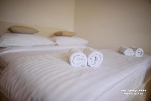 two rolls of towels sitting on top of a bed at Apartment/Room ''Dalmacija'' SINJ in Sinj