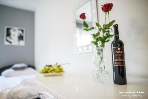 a bottle of wine and a vase of flowers on a table at Apartment/Room ''Dalmacija'' SINJ in Sinj
