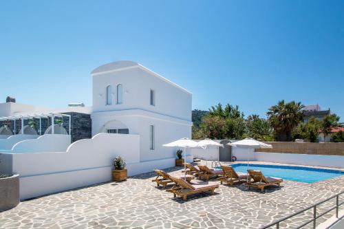 a pool with chairs and umbrellas next to a building at Alexander Studios & Suites - Adults Only in Faliraki