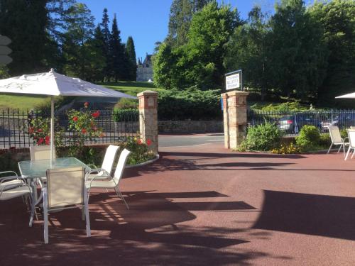 a patio with a table and chairs and an umbrella at Hôtel Bellevue Bagnoles Normandie in Bagnoles de l'Orne