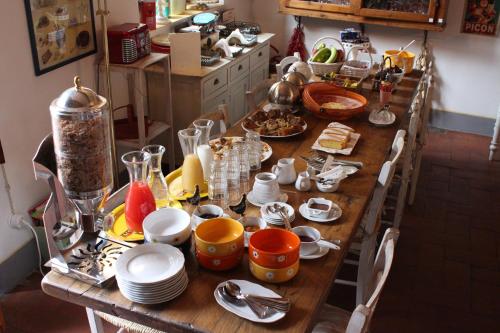 a wooden table with plates and utensils on it at Le Terrazze Del Chianti b&b Residenza d'Epoca e di Charme in Tavarnelle in Val di Pesa