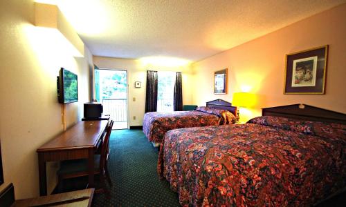 a hotel room with two beds and a desk at American Motel - Lenoir in Lenoir