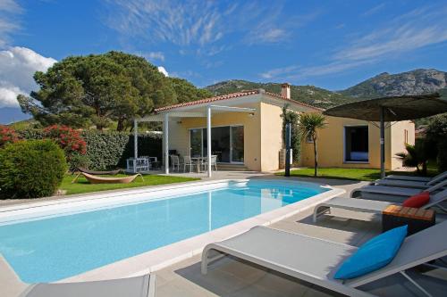 une piscine avec des chaises et une maison dans l'établissement Domaine Villas Mandarine Private Pools & Spa, à Calvi