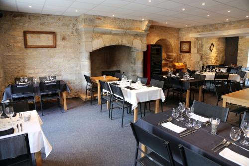 a restaurant with tables and chairs and a stone wall at Logis La Garissade in Labastide-Murat