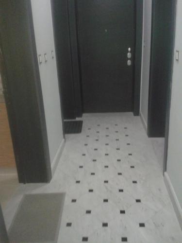 a hallway with a black door and a white tile floor at Super 36sqm Junior Suite in luxurious picturesque area in Piraeus