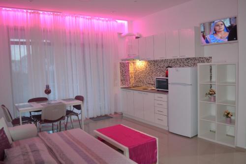 a kitchen with pink lighting and a table and a refrigerator at City Park Residence in Constanţa
