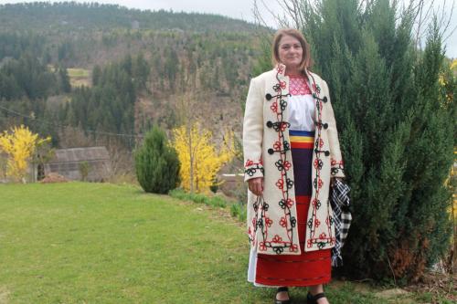 a woman is standing next to a bush at Arnica Montana in Arieşeni