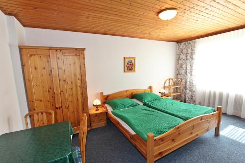 a bedroom with a wooden bed and a table at Pension Sybille in Ebensee