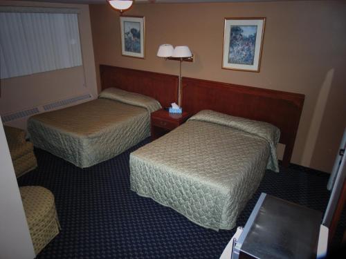 A bed or beds in a room at Canadiana Motel