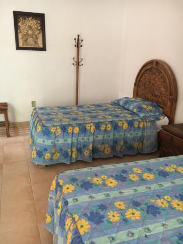 a bedroom with two beds and a cross on the wall at Hotel Posada Andaluz in Xochitepec