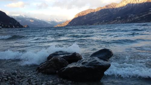 a group of rocks in the water with mountains at B&B L'erica in Oliveto Lario