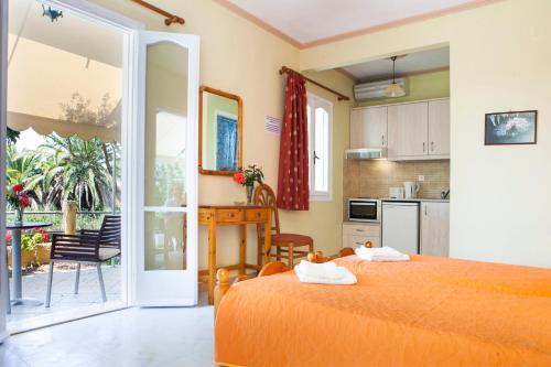 a bedroom with an orange bed and a kitchen at Tzivras Villa & Apartments in Lassi